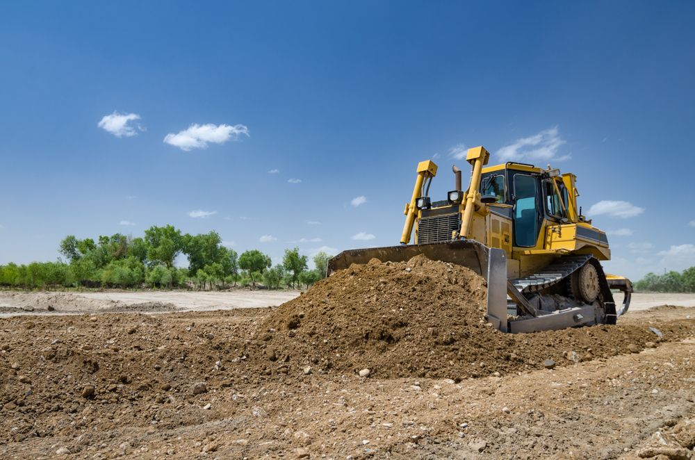 Yellow Bulldozer Pushing Dirt at a Construction Site Under a Blue Sky — Mike Barlow Earthmoving Pty Ltd in Rockhampton, QLD