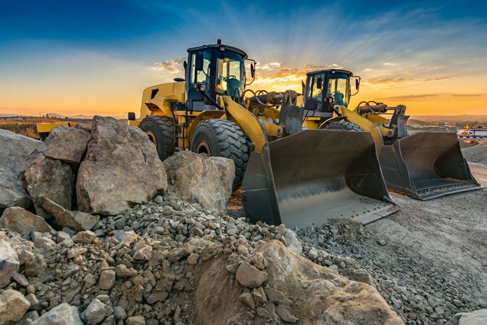 Two Yellow Bulldozers Pushing Rocks — Mike Barlow Earthmoving Pty Ltd in Rockhampton, QLD