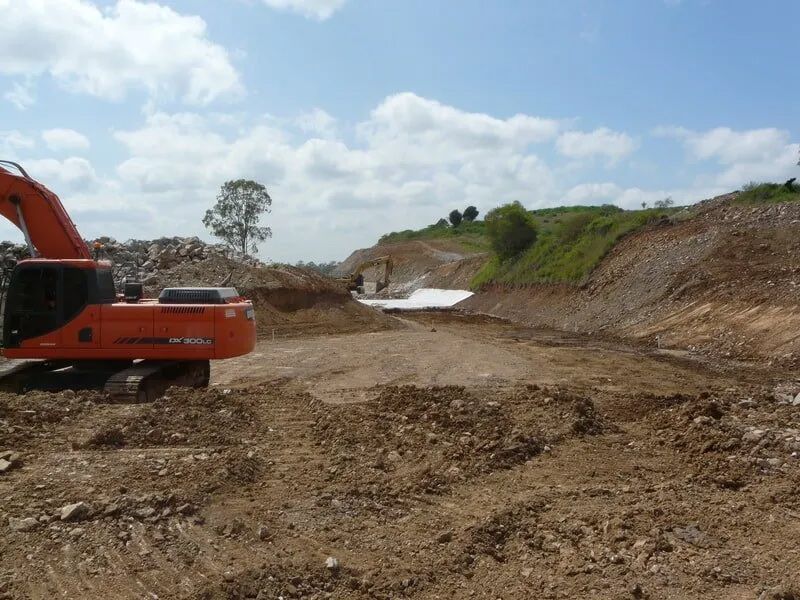 Red Excavator Constructing The Road By Removing The Dirt And Rocks — Mike Barlow Earthmoving Pty Ltd in Rockhampton, QLD