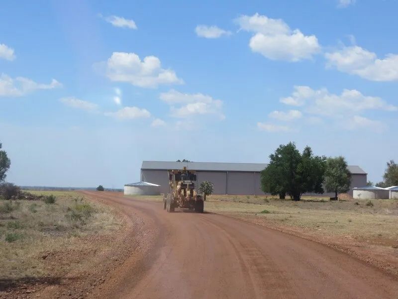 Road With Yellow Excavator Driving Over It — Mike Barlow Earthmoving Pty Ltd in Rockhampton, QLD