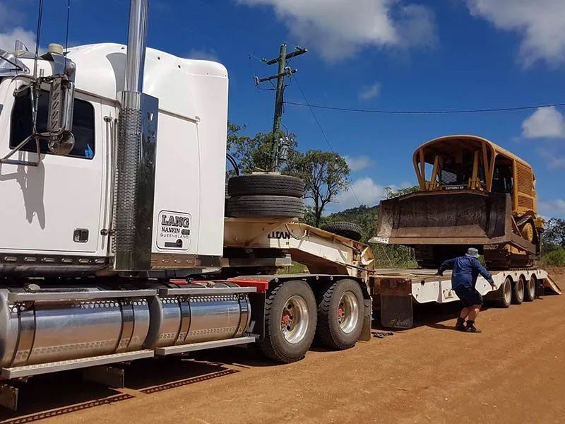 White Semi Truck Towing A Bulldozer On The Trailer — Mike Barlow Earthmoving Pty Ltd in Rockhampton, QLD