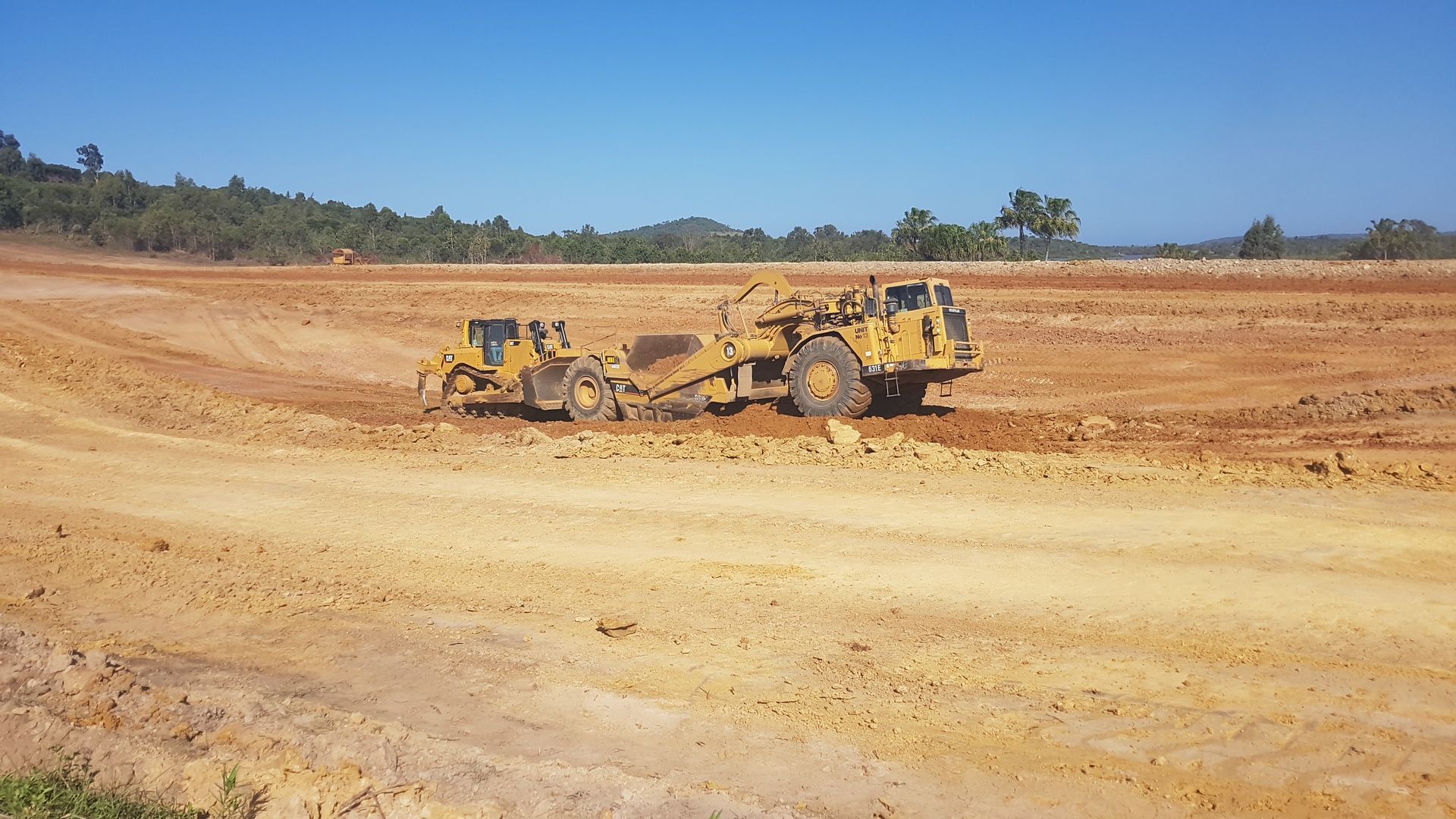 A Dump Truck Is Dumping Dirt Into a Field — Mike Barlow Earthmoving Pty Ltd in Gladstone, QLD