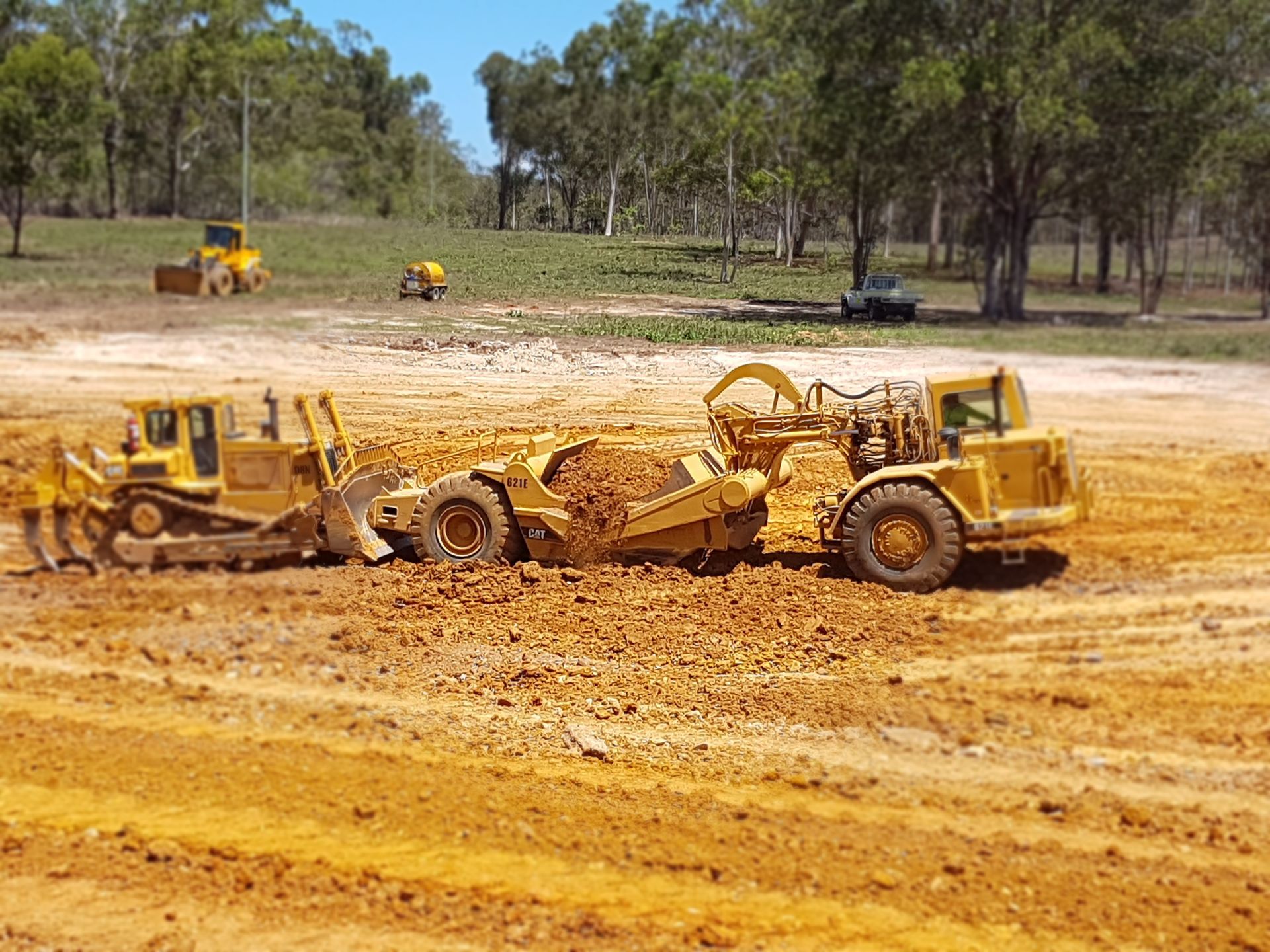 A Yellow Tractor Is Driving Through a Pile of Rocks — Mike Barlow Earthmoving Pty Ltd in Gladstone, QLD