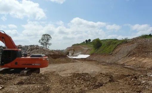 A Large Orange Excavator Is Working On A Dirt Road — Mike Barlow Earthmoving Pty Ltd in Rockhampton, QLD