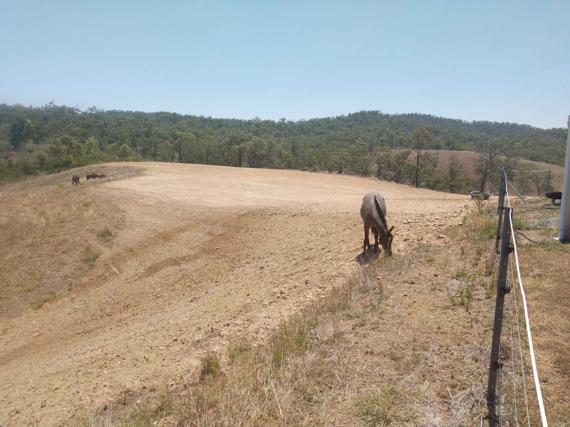 An Excavator Is Digging a Hole in The Dirt in A Field — Mike Barlow Earthmoving Pty Ltd in Gladstone, QLD