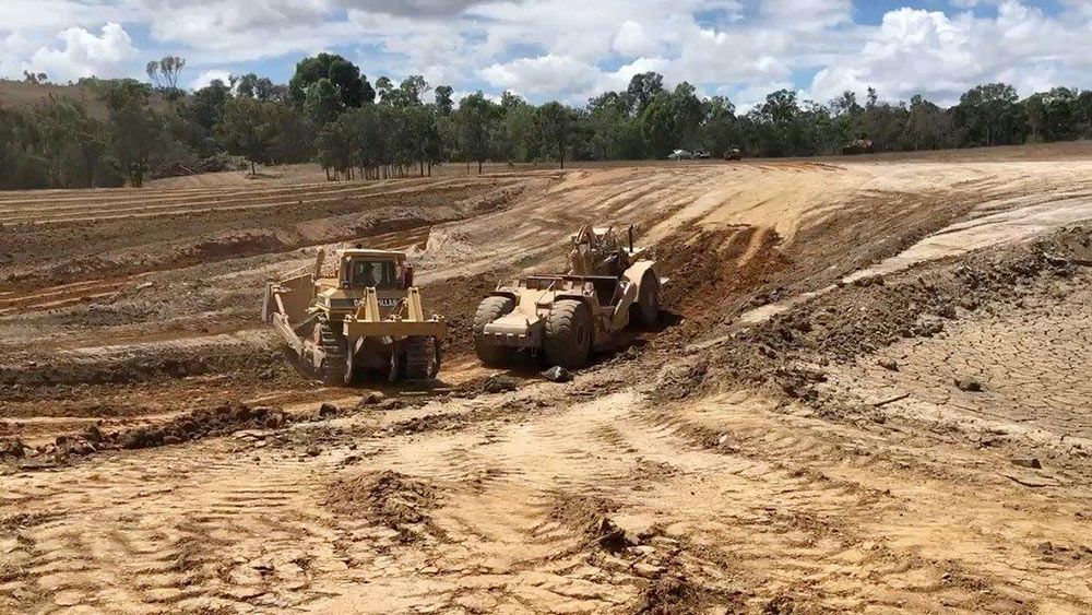 Two Bulldozers Are Working In A Muddy Field — Mike Barlow Earthmoving Pty Ltd in Rockhampton, QLD