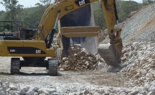 A Cat Excavator Is Working On A Rocky Hillside — Mike Barlow Earthmoving Pty Ltd in Rockhampton, QLD