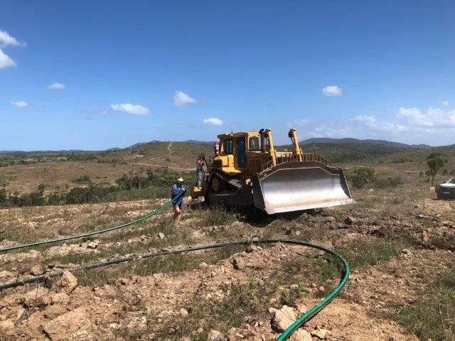 A Bulldozer Is Parked On Top Of A Dirt Field Next To A Hose — Mike Barlow Earthmoving Pty Ltd in Rockhampton, QLD