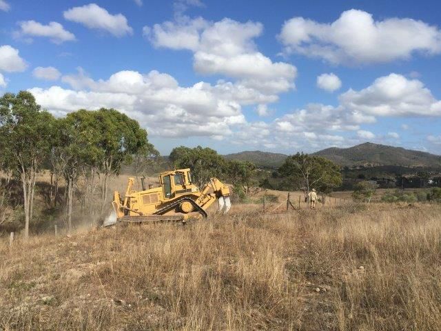 Yellow Excavator Cleaning Land In The Dirty Field — Mike Barlow Earthmoving Pty Ltd in Rockhampton, QLD