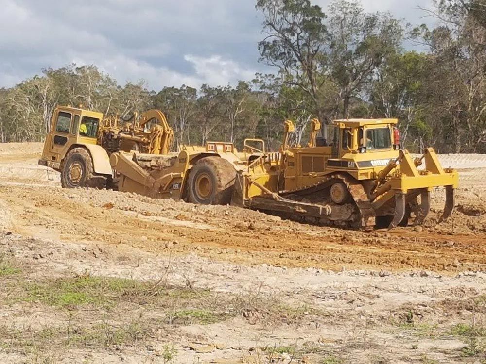 Two Yellow Big Excavator Cleaning On The Dirt Field — Mike Barlow Earthmoving Pty Ltd in Rockhampton, QLD