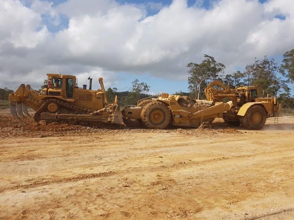 Two Yellow Bulldozers Cleaning land For Road Construction — Mike Barlow Earthmoving Pty Ltd in Rockhampton, QLD
