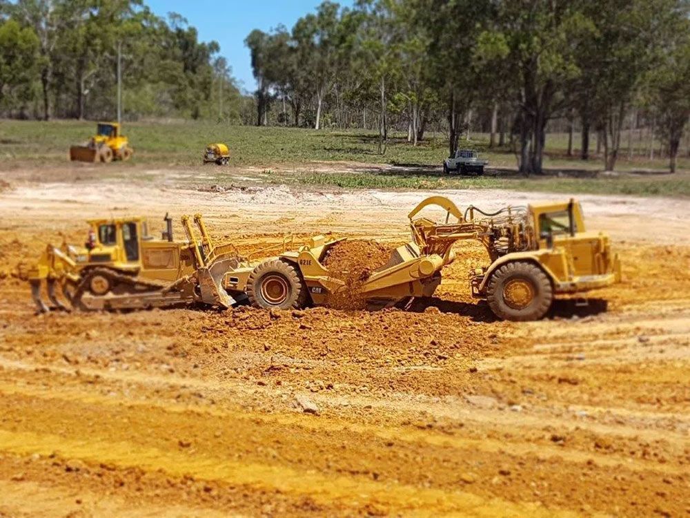 Four Yellow Big Excavator In The Dirty Field Cleaning Land — Mike Barlow Earthmoving Pty Ltd in Rockhampton, QLD