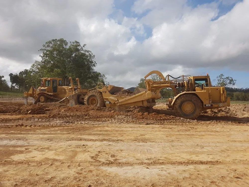 Two Yellow Big Excavator On The Dirty Field For Land Cleaning — Mike Barlow Earthmoving Pty Ltd in Rockhampton, QLD