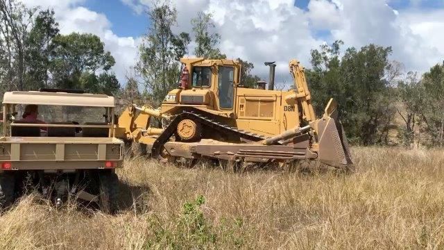 A Yellow Bulldozer Is Driving Through A Field — Mike Barlow Earthmoving Pty Ltd in Rockhampton, QLD