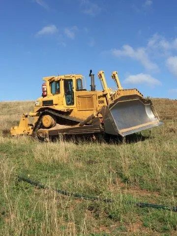 A Bulldozer Is Parked in A Grassy Field — Mike Barlow Earthmoving Pty Ltd in Rockhampton, QLD