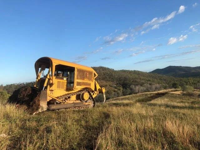 Yellow Big Excavator Cleaning In The Dirt Field — Mike Barlow Earthmoving Pty Ltd in Rockhampton, QLD