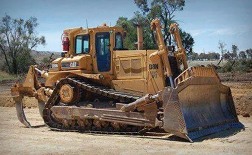 A Bulldozer Is Parked On The Side Of A Dirt Road — Mike Barlow Earthmoving Pty Ltd in Rockhampton, QLD