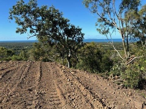 A Yellow Tractor Is Driving Through A Dirt Field — Mike Barlow Earthmoving Pty Ltd in Rockhampton, QLD