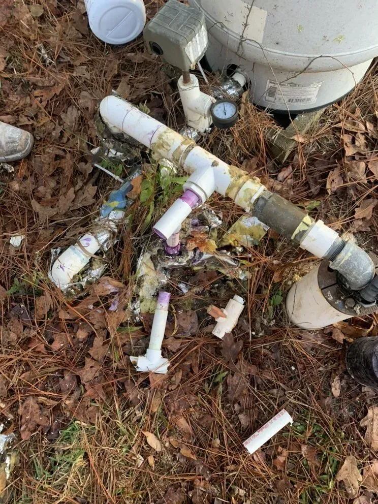 A bunch of plastic pipes are laying on the ground.
