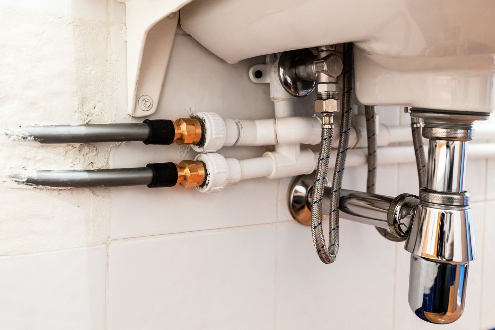 A bathroom sink with a lot of pipes underneath it.