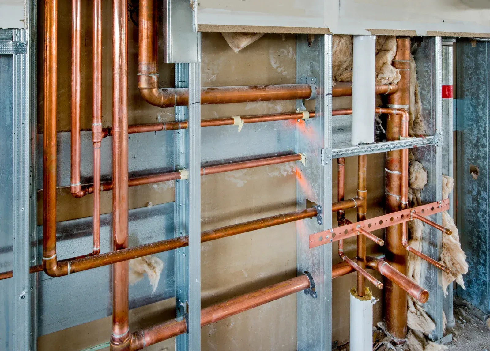A bunch of copper pipes are hanging on a wall.