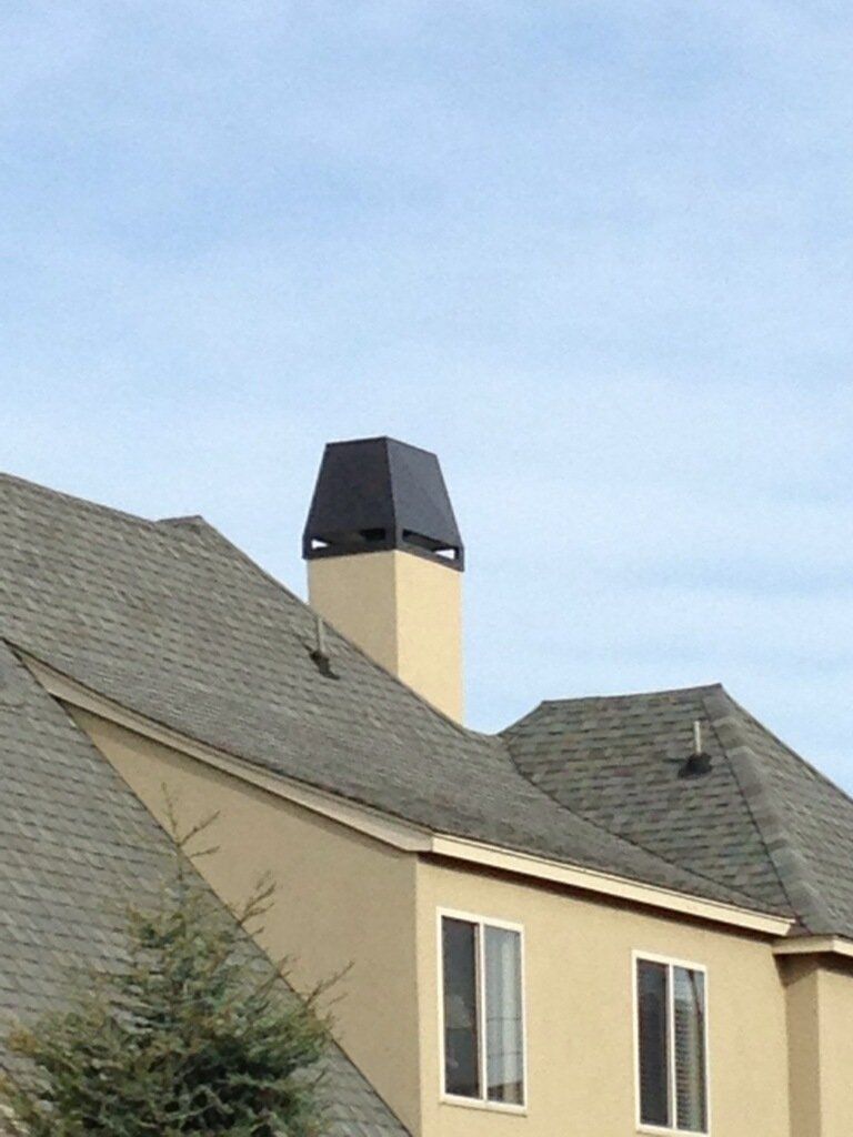 House roof with a black chimney against a blue sky