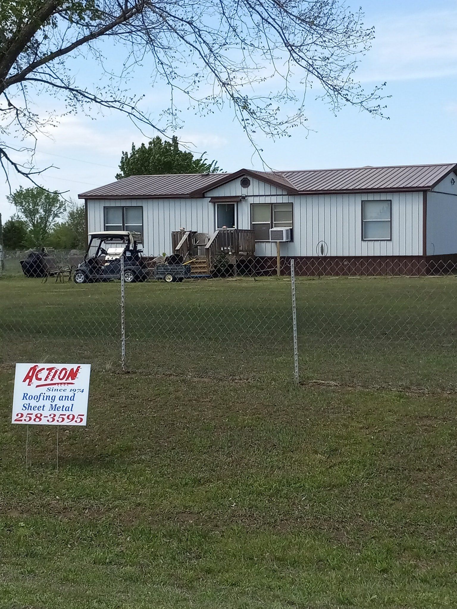 Single-story house with a porch and lawn; a small sign reads “Action” in the foreground.