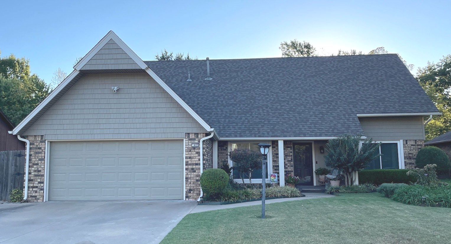 Suburban house with a two-car garage, gabled roof, front porch, and well-kept lawn
