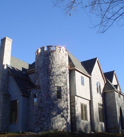 Stone castle-like house with a round turret and steep roofs against a blue sky