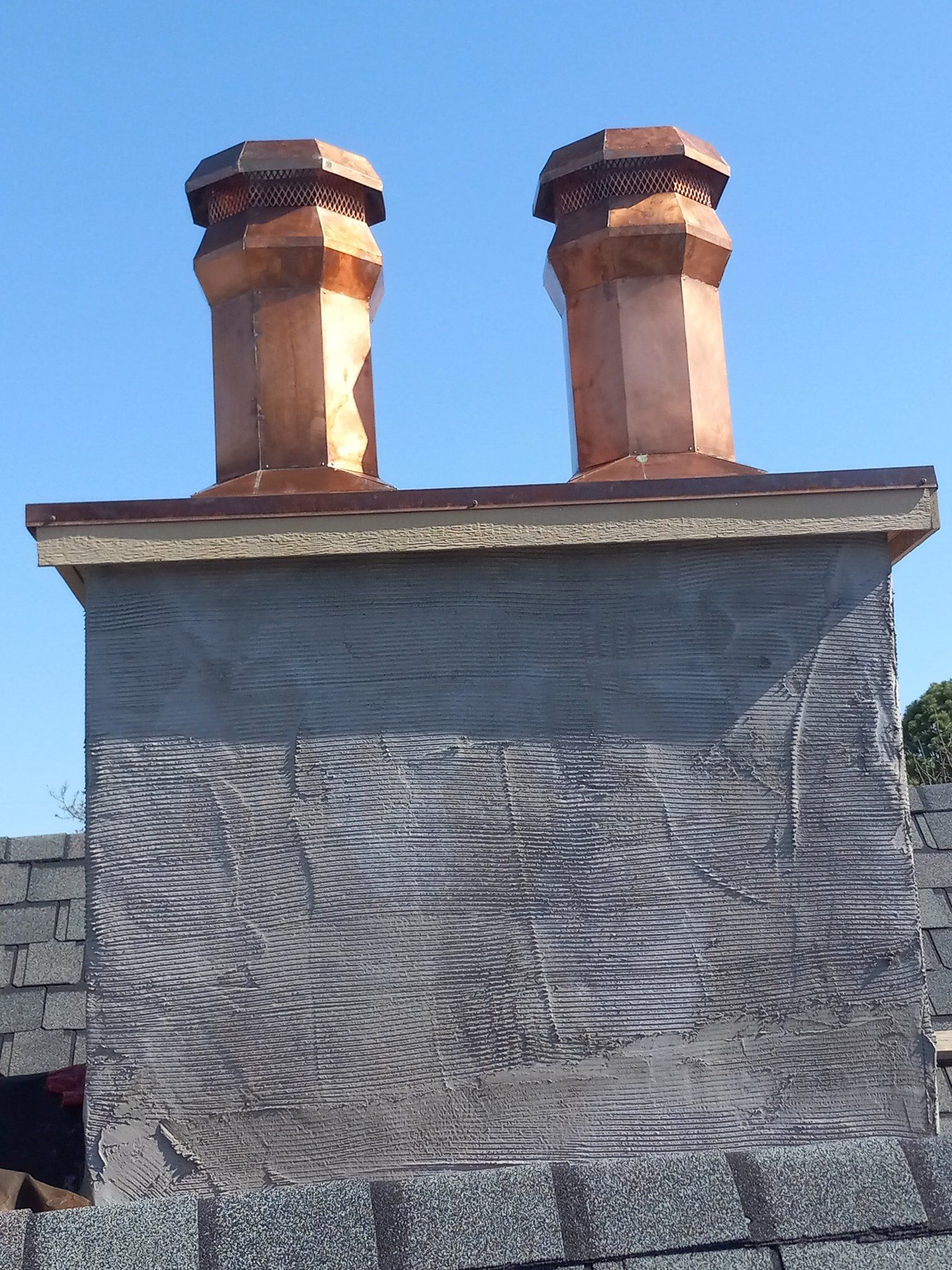 Stone chimney with two copper chimney pots against a blue sky