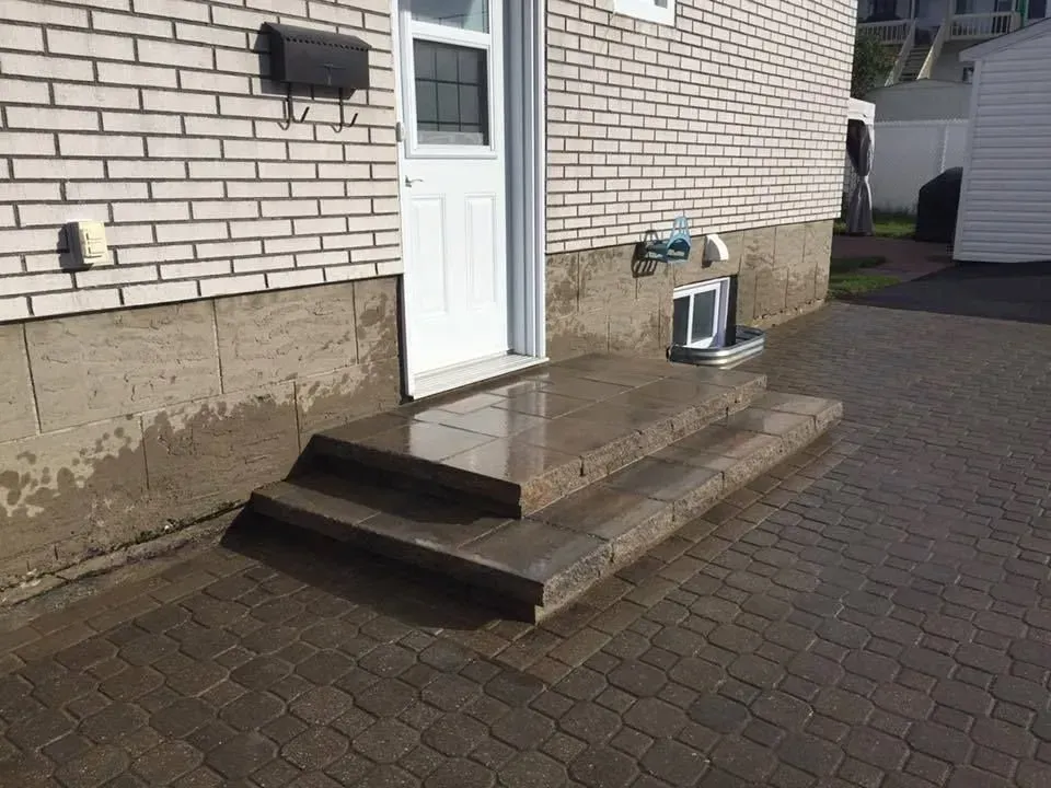 Porte d'entrée avec une petite rampe en bois et des marches à côté d'une allée en briques