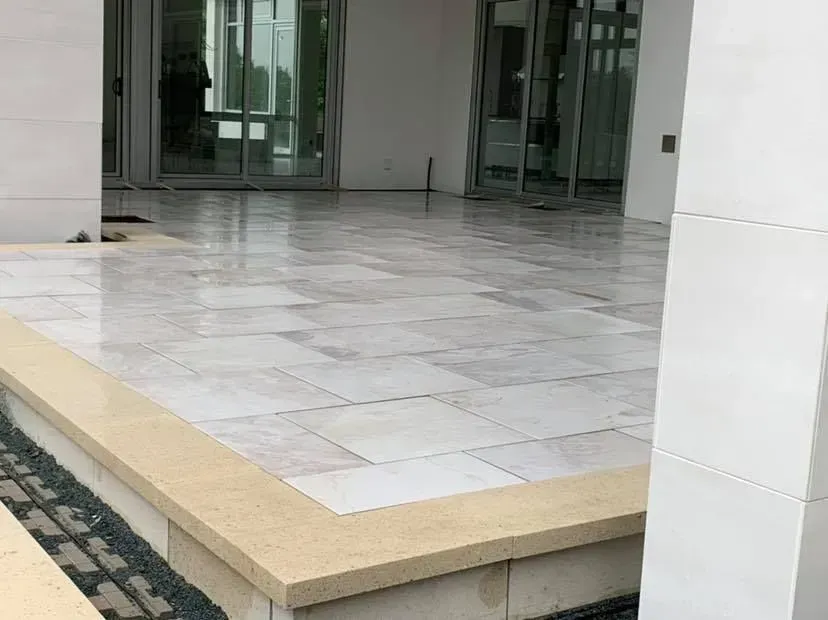Entrée carrelée vide avec marche beige et portes vitrées dans un bâtiment moderne