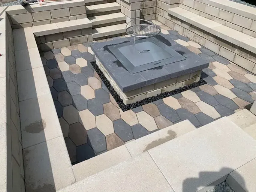 Cour intérieure en pierre avec une plateforme carrée grise centrale et un sol en carreaux hexagonaux, encadrée de murets.