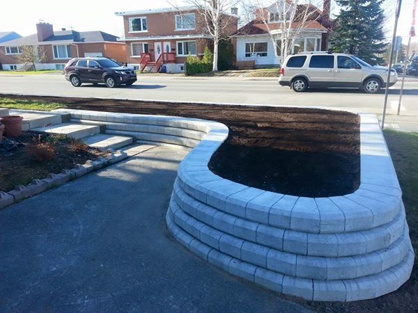 Muret de jardinière en pierre incurvé entourant un patio en contrebas dans un paysage urbain de banlieue