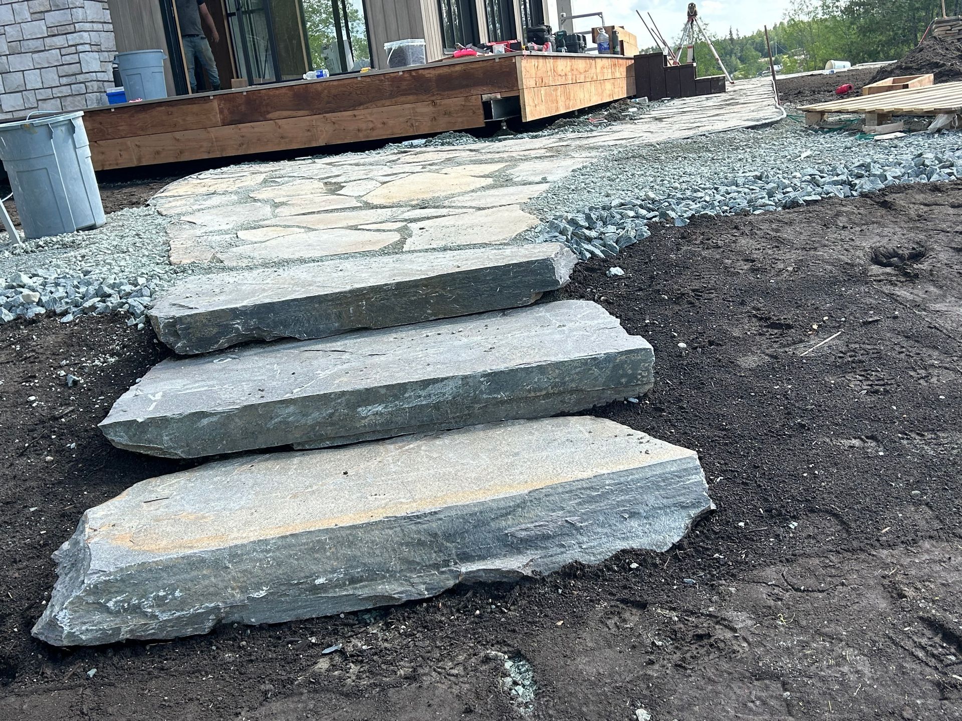 Escaliers en pierre inachevés menant à un chemin de gravier à côté d'une maison en construction