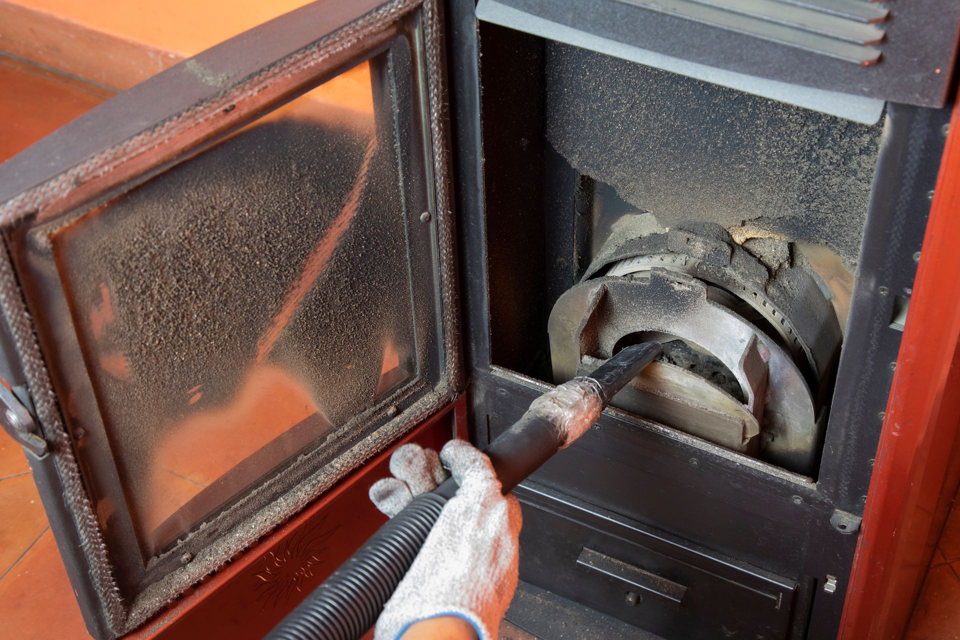 A person is cleaning a stove with a vacuum cleaner.
