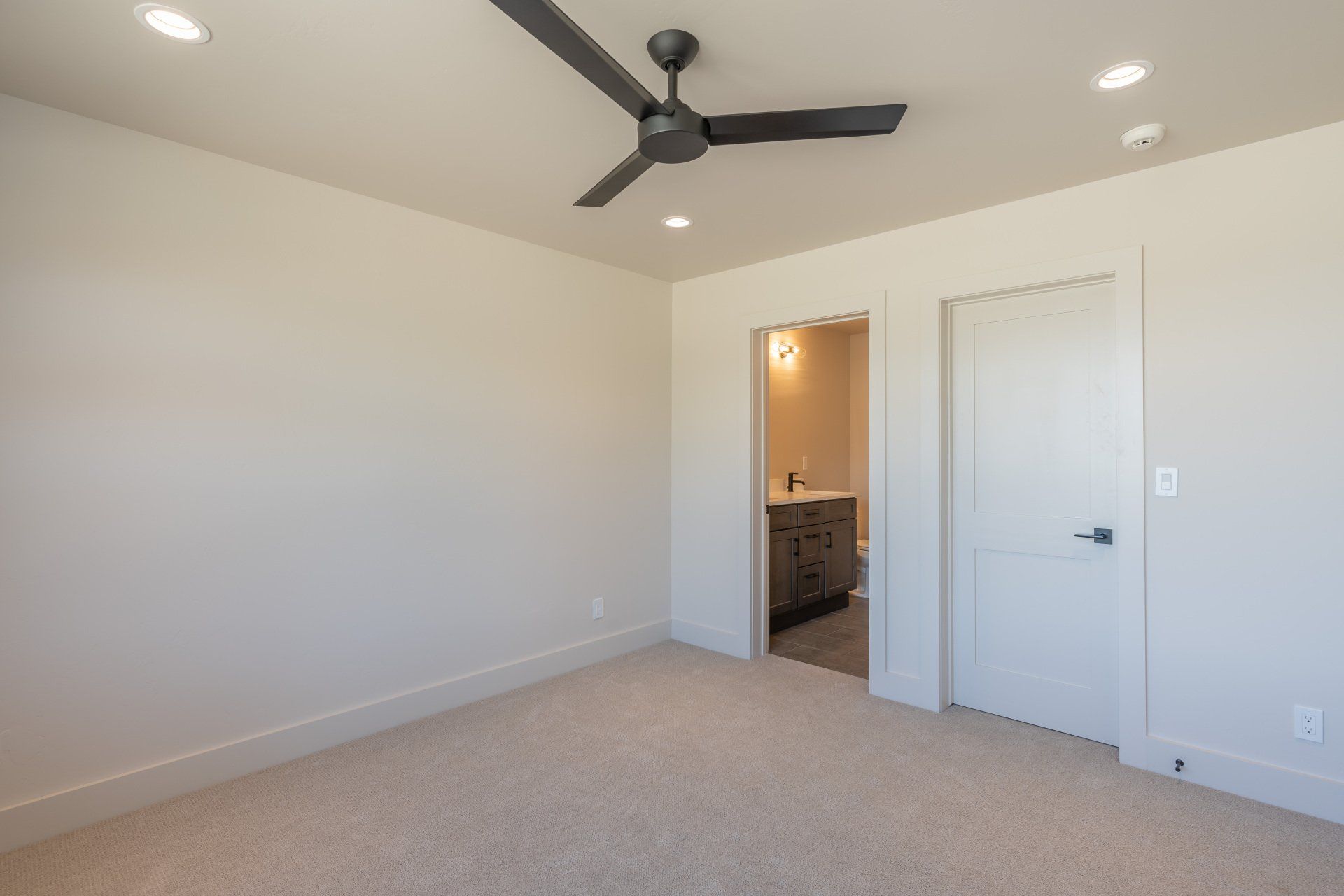 An empty bedroom with a ceiling fan and a bathroom.