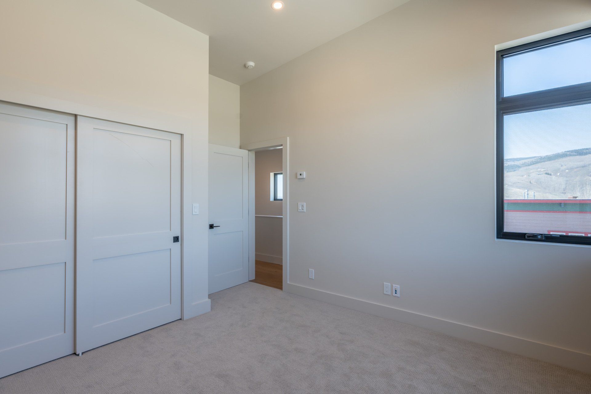 An empty bedroom with a window and a closet.
