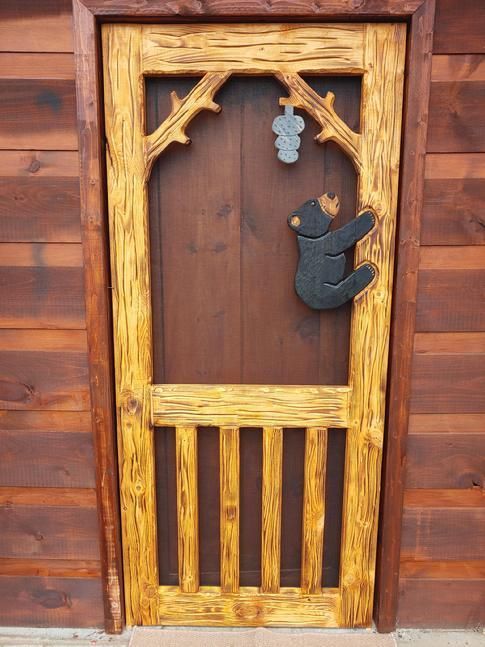 Door has a bear cub climbing towards an overhaning beehive.