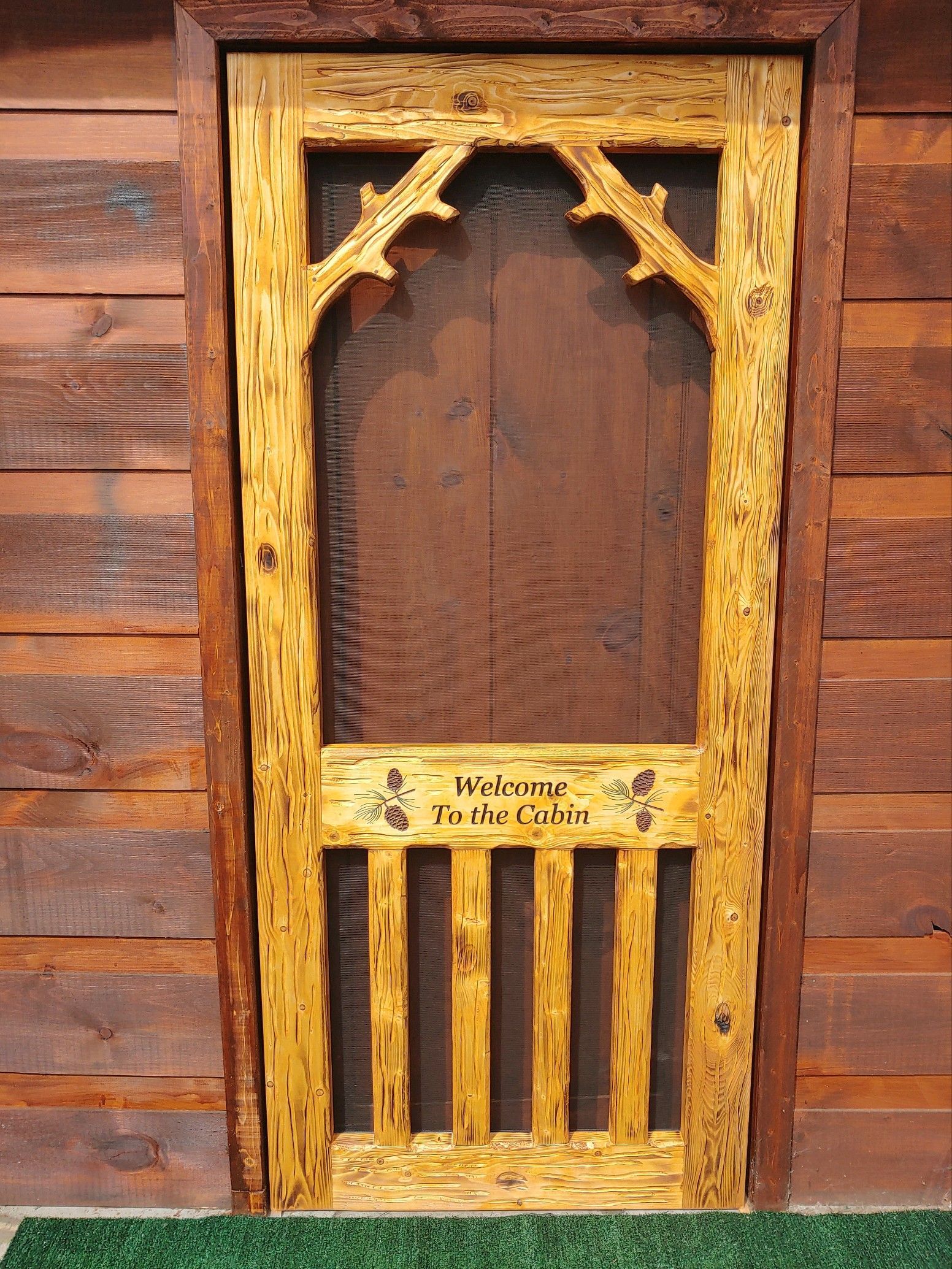 Rustic screen door with carved middle rail saying 
