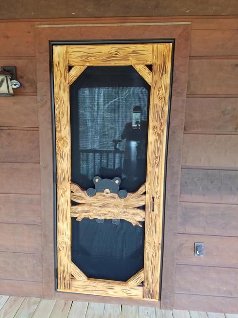 Door shows a bear cub hanging on to a log