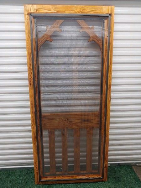 a wooden screen door is sitting in front of a white garage door .