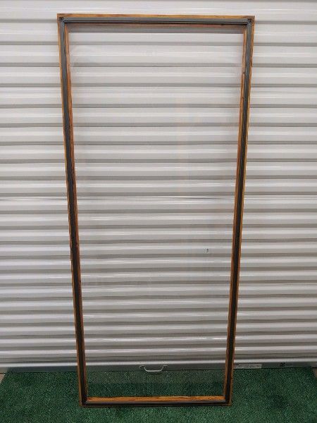 a wooden frame with marine grade vinyl window is sitting on top of a green carpet in front of a garage door .