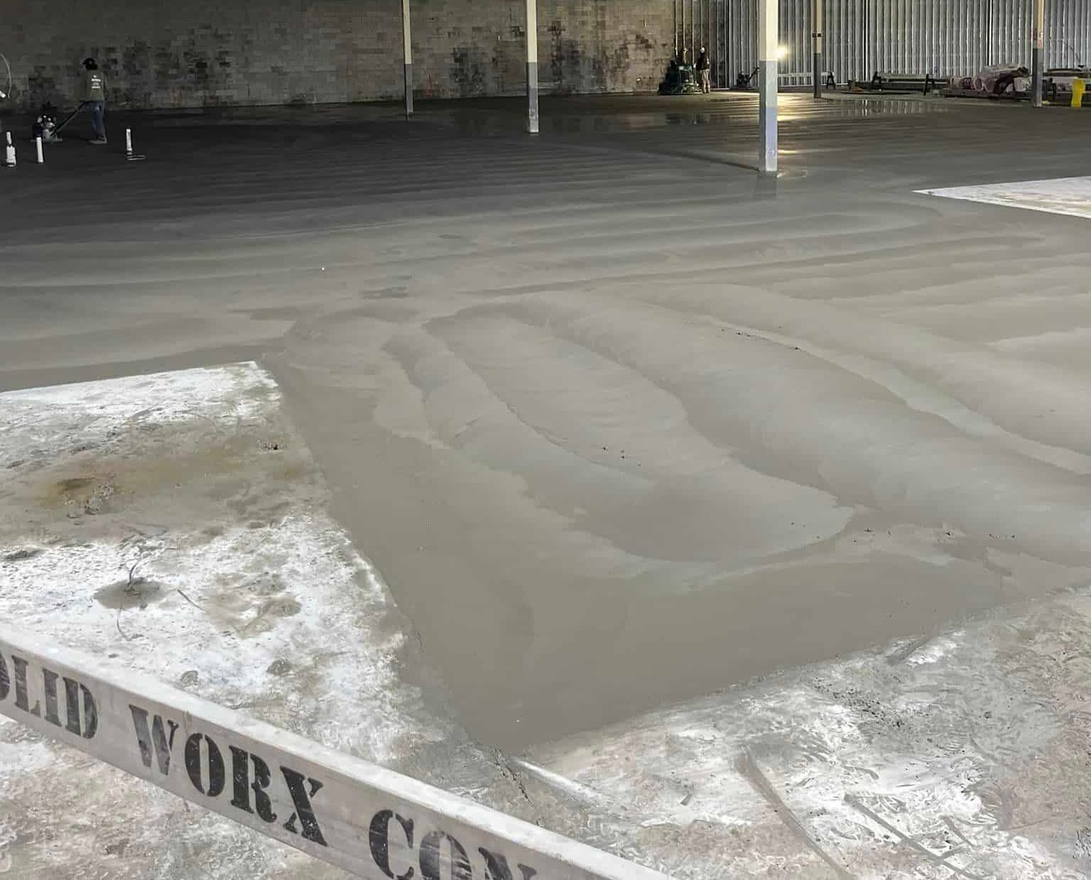 A concrete floor is being installed in a warehouse.