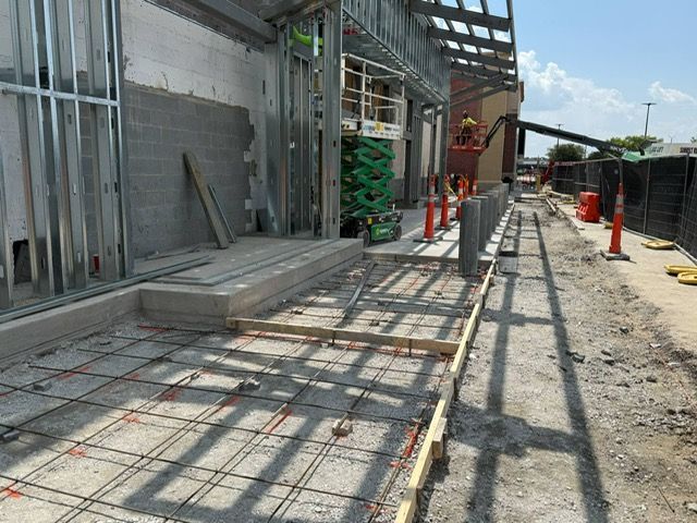 A concrete walkway is being built in front of a building under construction.