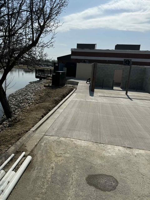 A concrete walkway leading to a building next to a body of water