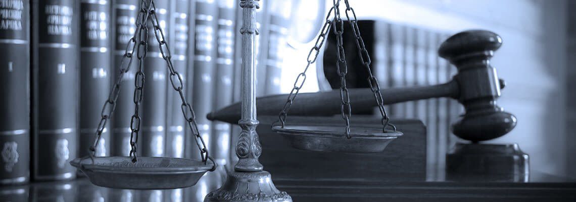 A judge 's gavel and scales of justice in front of a row of books. A judge 's gavel and scales of justice in front of a row of books.