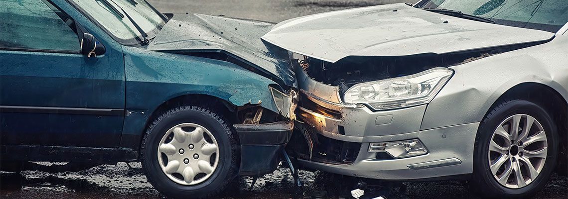 A blue car and a silver car are involved in a car accident.