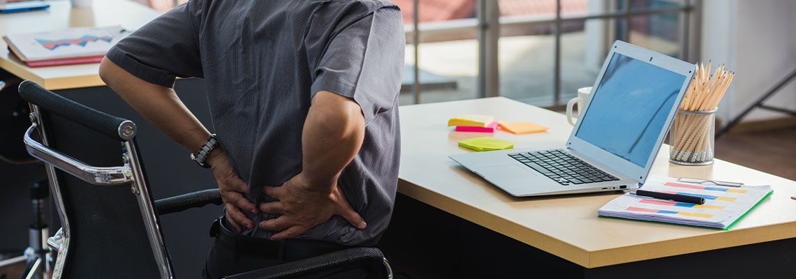 A man is sitting at a desk with his hands on his back. A man is sitting at a desk with his hands on his back.