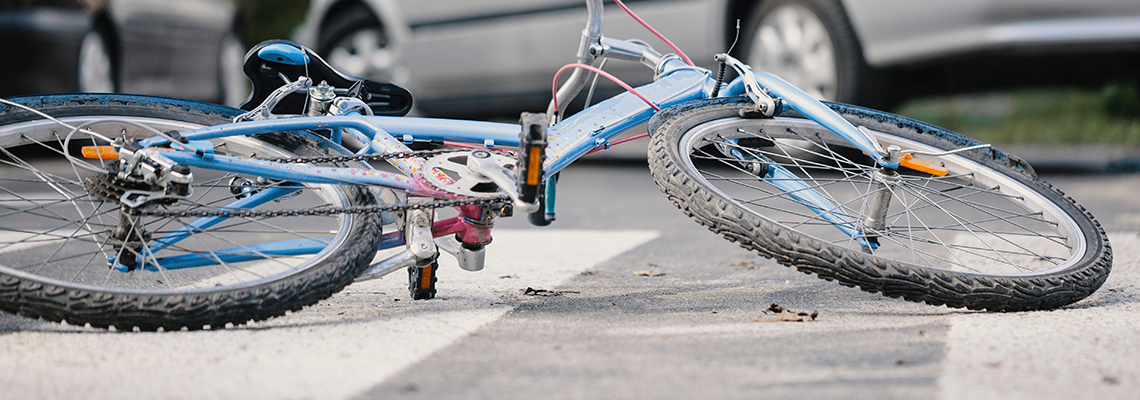 A bicycle is laying on the ground after being hit by a car.